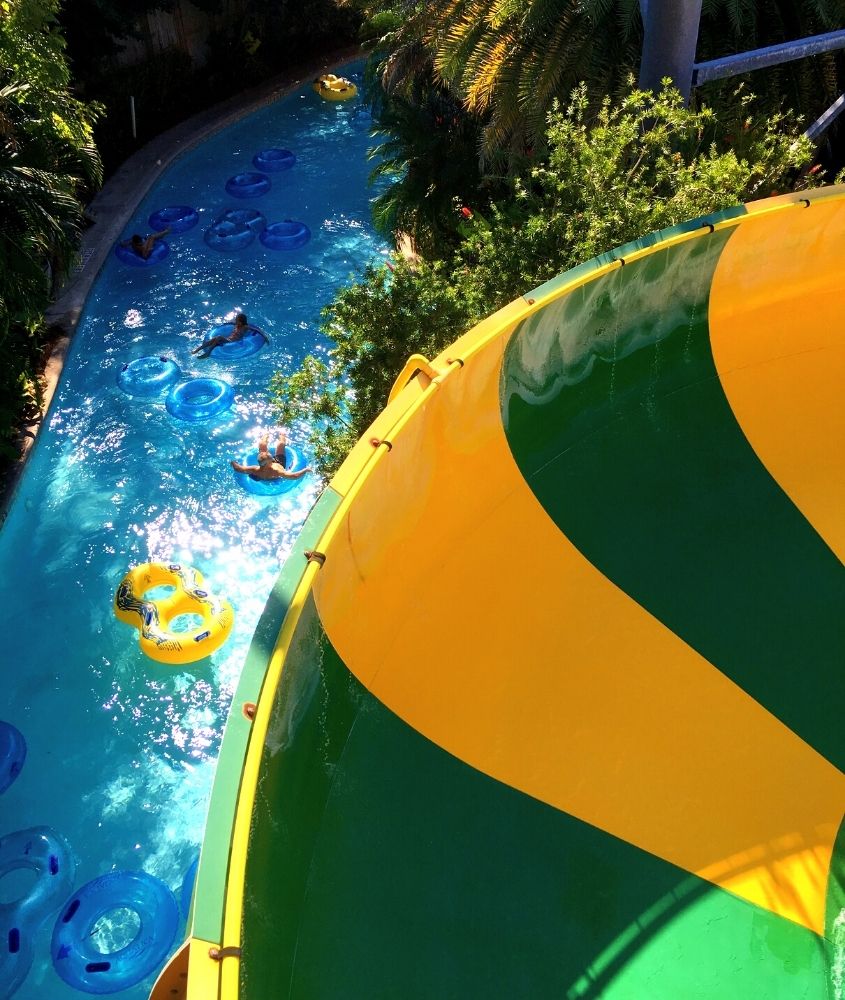 vista aérea de pessoas em piscina cercada de árvores, durante dia ensolarado em eco parque arraial d'ajuda, um dos melhores parques para crianças do país localizado na bahia
