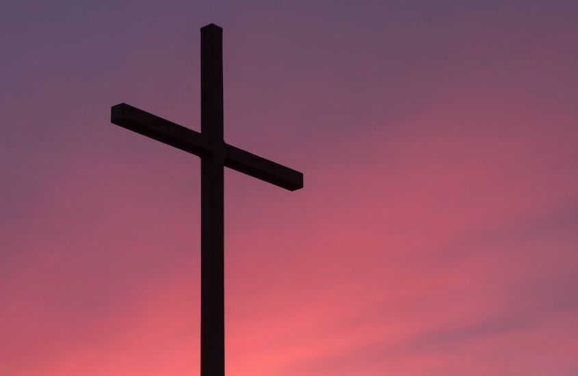 cruz marrom com céu rosa e azul, durante entardecer