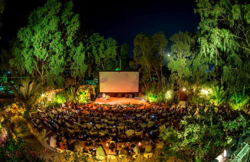 Durante a noite, Cine Kamari em Santorini com pessoas e árvores ao redor