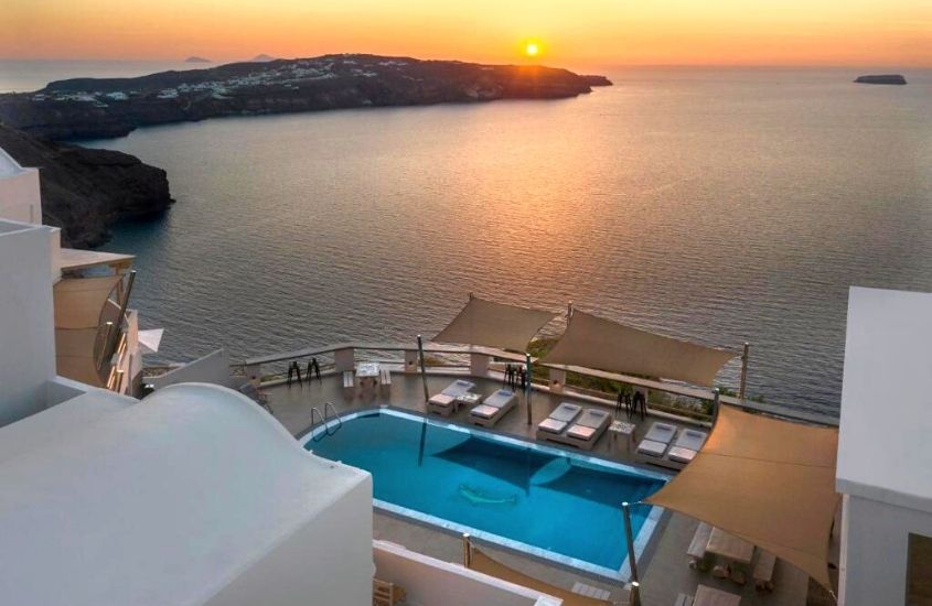 vista aérea, durante entardecer, de cadeiras e piscina em terraço de grand view, hotel de frente para o mar em megalochori