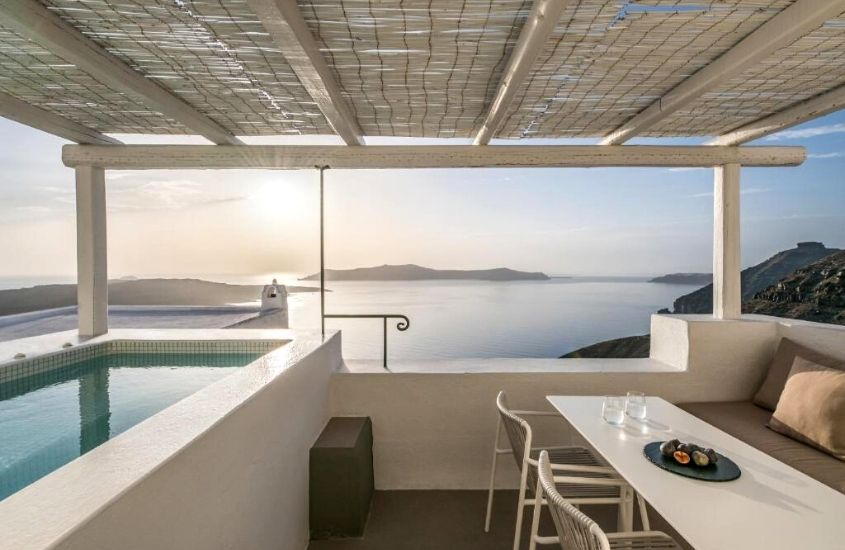piscina, cadeiras e mesa, durante dia ensolarado, em terraço de frente para o mar do enigma suites, hotel romântico em fira