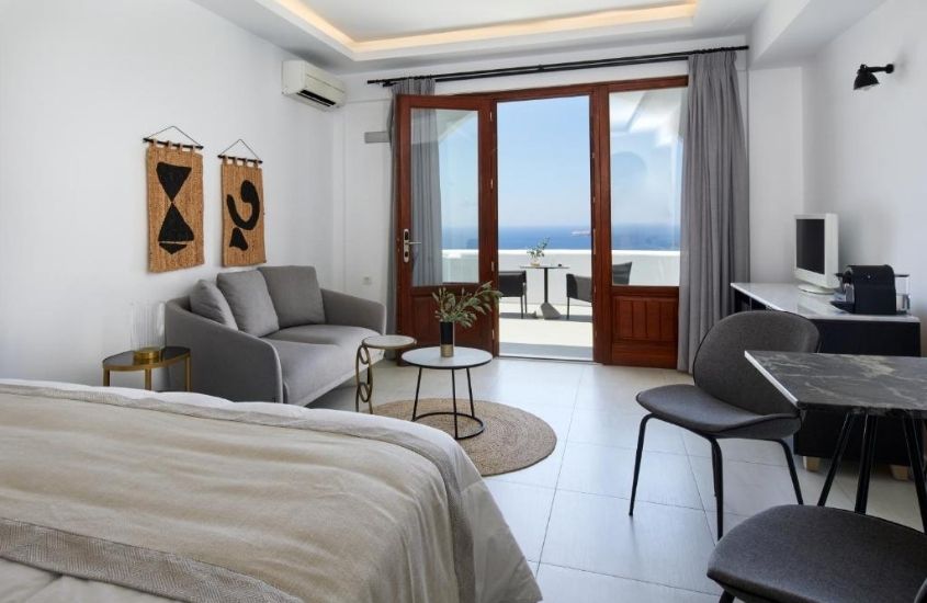 cama de casal, sofá e cadeiras em suíte com varanda de frente para o mar do petit palace suites hotel, um dos melhores hotéis em santorini