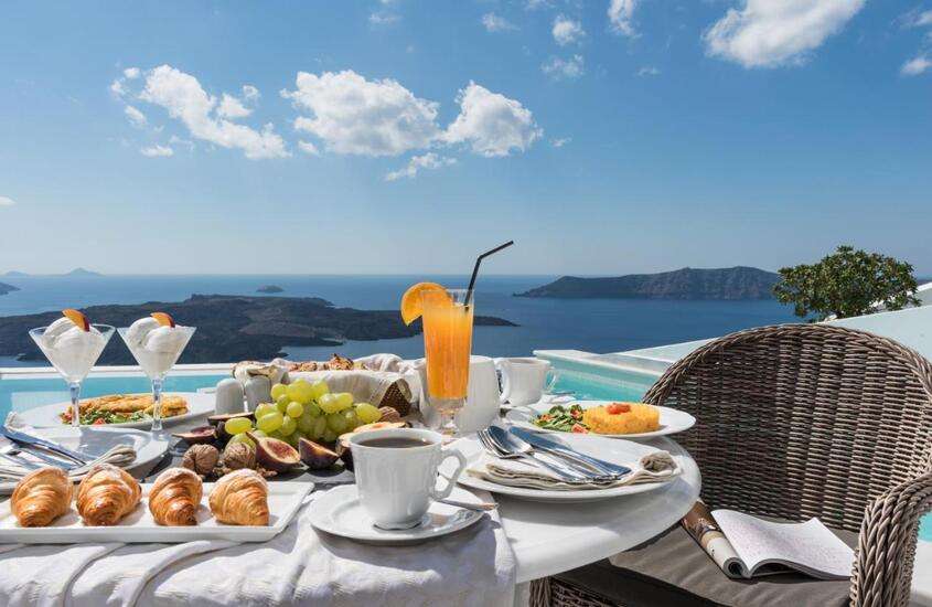 durante o dia, café da manhã servido em mesa de varanda de hotel em Santorini com vista para o mar