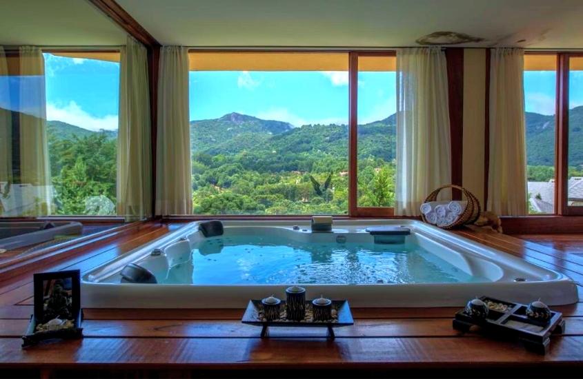 banheira de hidromassagem com vista para as montanhas, durante o dia, na pousada spa mirante da colyna, uma das pousadas românticas mg localizada em monte verde