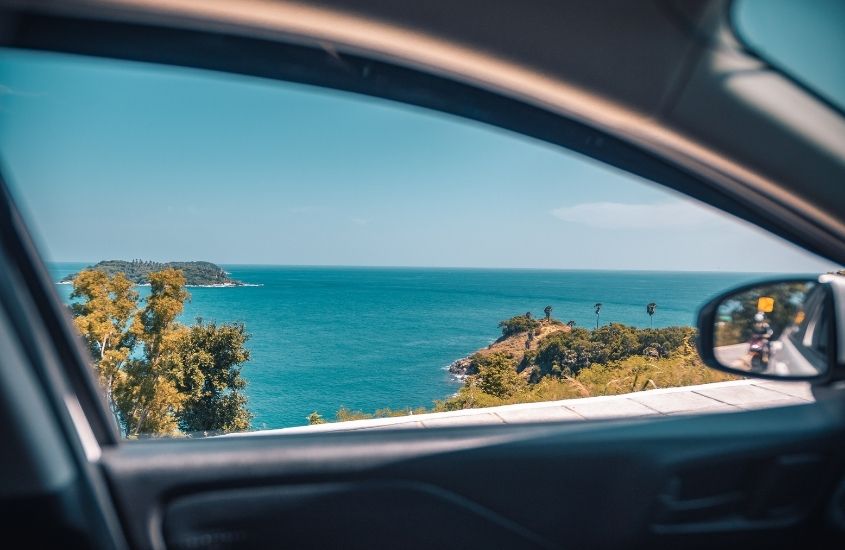 mar azul, durante o dia, visto de janela em viagem de carro pelo nordeste
