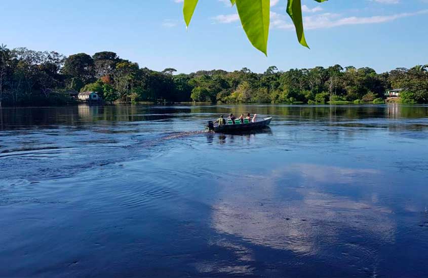 Em um dia de sol, rio perto de um dos hotéis de selva em manaus com barco navegando e floresta ao redor
