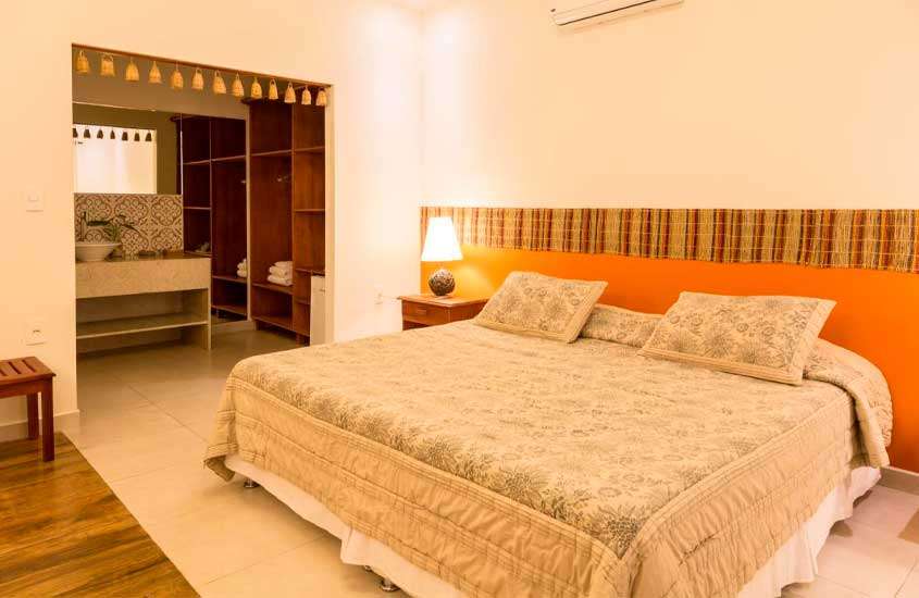 Quarto de um dos hotéis de selva no amazonas com cama de casal, ar-condicionado, criado, pia com planta decorativa, armários e toalhas