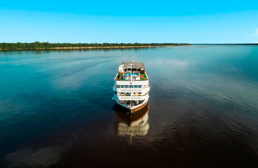 Em um dia ensolarado, um hotel em forma de navio, em rio Amazonas com a floresta no fundo