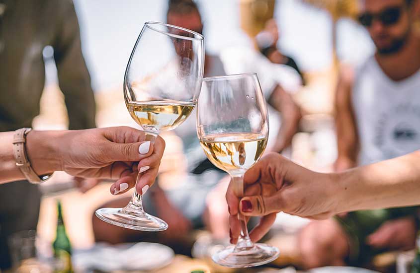 durante o dia, pessoas brindando com taças de vinho em víniola em Mykonos
