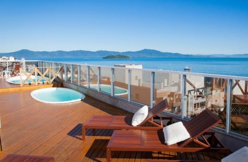 piscinas e espreguiçadeiras em terraço com vista para o mar em Al Mare Hotel um dos hotéis em Florianópolis perto da praia