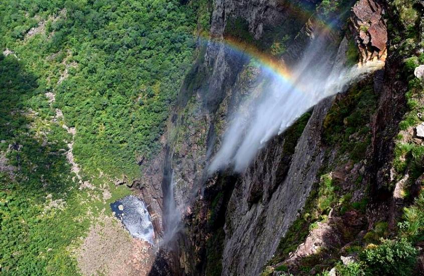 vista de cima para baixo de arco íris em queda d'água de cachoeira, durante dia ensolarado