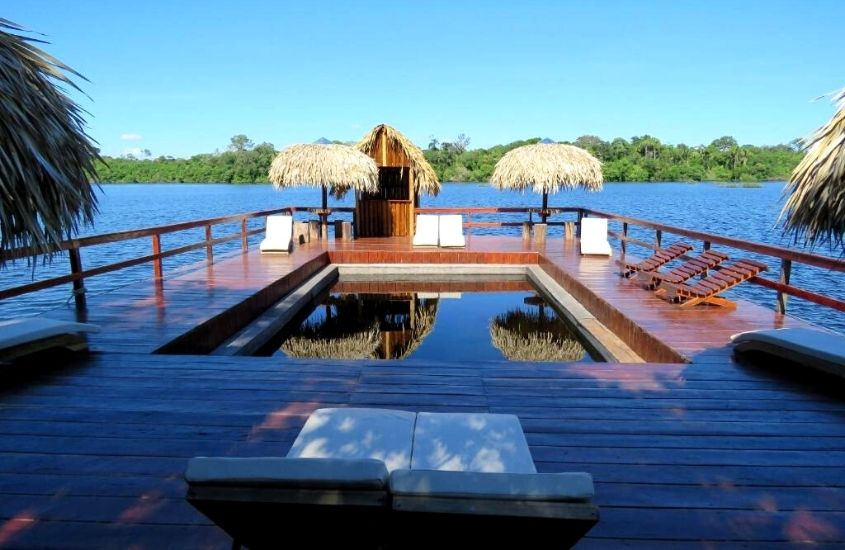 espreguiçadeiras e piscina em deck de frente para o rio, durante o dia em Juma Amazon Lodge