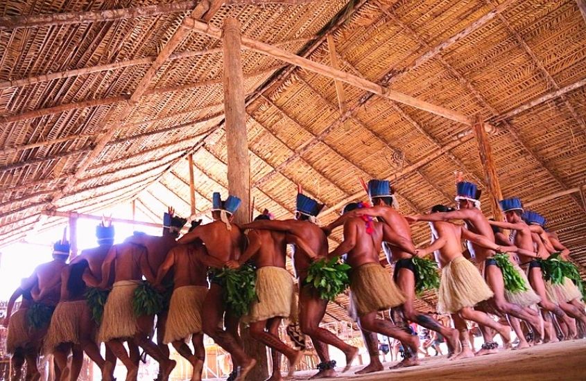 índios dançando dentro de estrutura de palha