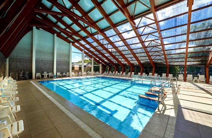 espreguiçadeiras ao redor de piscina coberta na área de lazer do Dall’Onder Grande Hotel