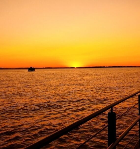 barco em mar, durante o pôr do sol em orla guaíba, um dos principais pontos turísticos de porto alegre