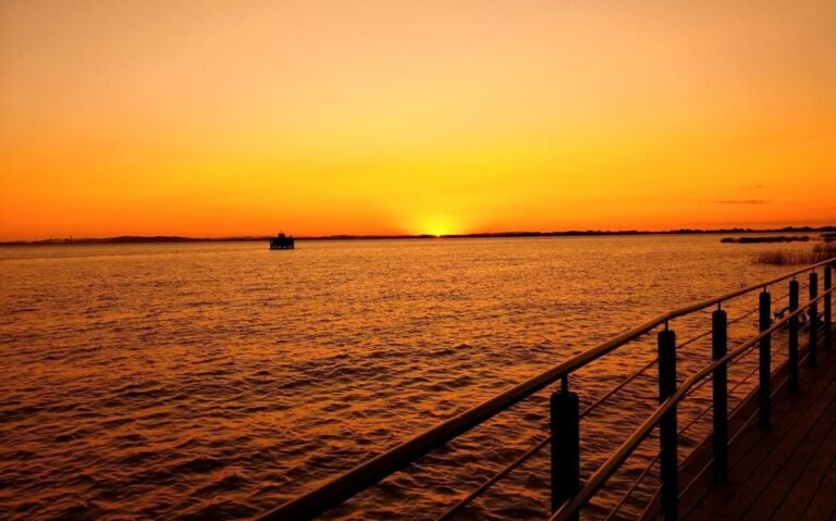 barco em mar, durante o pôr do sol em orla guaíba, um dos principais pontos turísticos de porto alegre