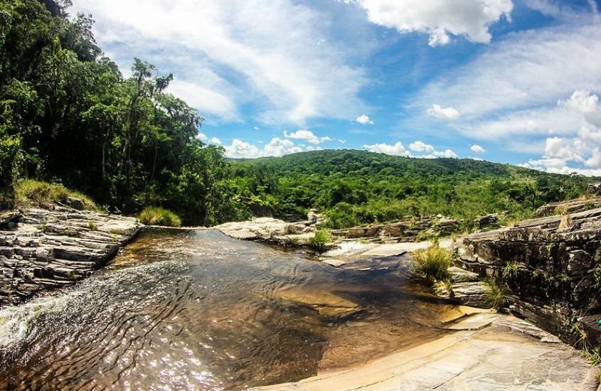 piscina natural cristalina cercada de árvores, durante dia ensolarado em São Thomé das Letras, um destino para onde viajar no Brasil