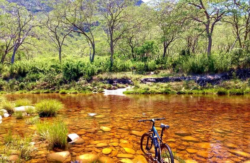bicicleta em cima lago cercado de árvores, durante o dia na serra do cipó