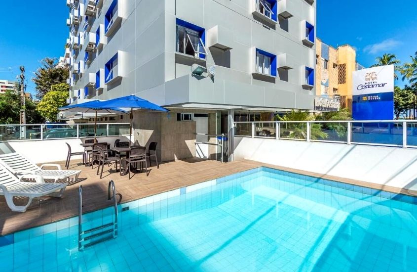 espreguiçadeiras em frente a piscina, em hotel costamar, durante dia de sol