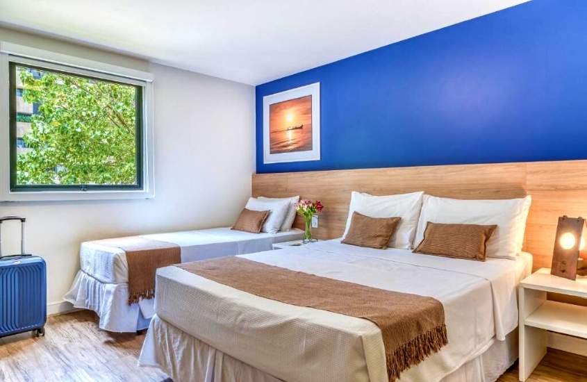 camas de casal e solteiro e mala de viagem em suíte de Cais da Praia Hotel, uma das melhores opções na lista de hotéis em maceió