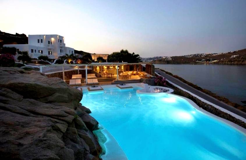 vista de cima de piscina com vista para o mar, durante entardecer em área de lazer de Dreambox Mykonos Suites, excelente hostel em mykonos