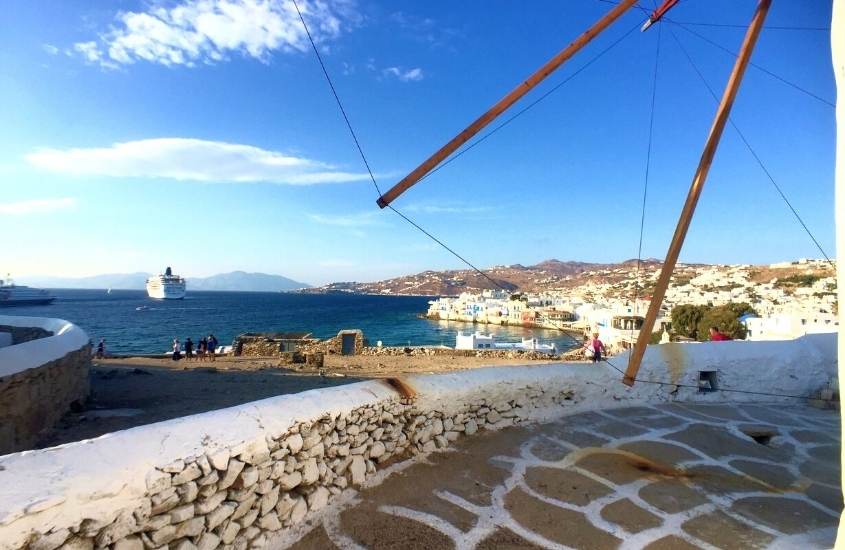 pessoas em mirante, observam navio em mar, durante o dia nos arredores da cidade de mykonos