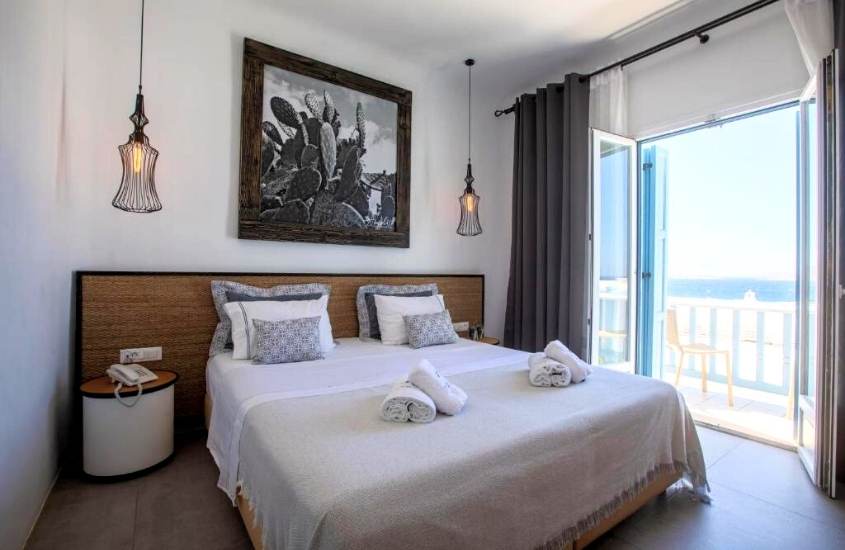 travesseiros e toalhas de banho em cima de cama de casal em suíte com varanda de Harmony Boutique Hotel, melhores hotéis em mykonos