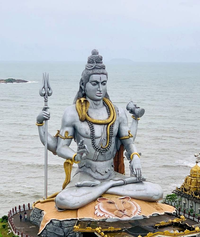 escultura gigante de deus indiano em frente ao mar, durante o dia