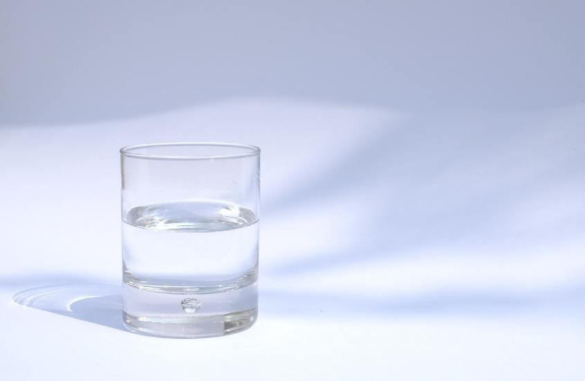 copo de vidro com água em cima de mesa branca