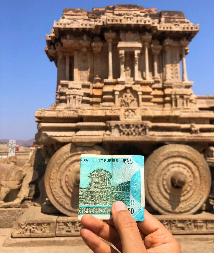 pessoa segura nota de rupees em frente a monumento da Índia durante o dia