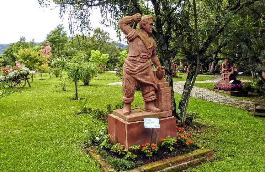 escultura de pedra de homem cercada de árvores, durante o dia em parque esculturas pedras do silêncio