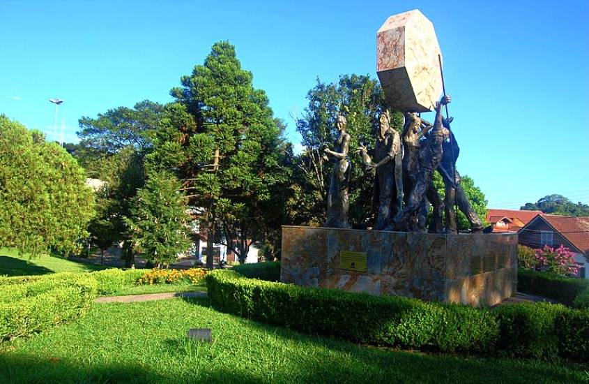 estátua de sete pessoas, conhecida como Monumento do Cooperativismo, rodeada de árvores durante dia ensolarado em nova petrópolis