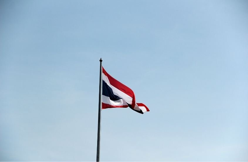 Bandeira da tailândia, que possui listras vermelhas, brancas e azul, balançando em mastro