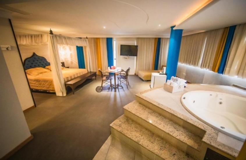 cama de casal, cadeiras, mesa redonda e banheira de hidromassagem redonda em suíte de Tri Hotel Executive Caxias