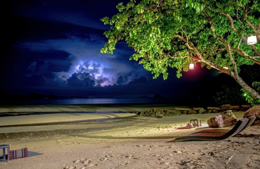 espreguiçadeiras em areia de praia, durante a noite em krabi