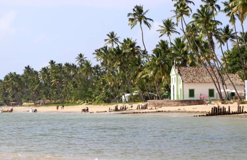 vista panorâmica de igreja e coqueiros em frente ao mar da praia dos carneiros, durante o dia