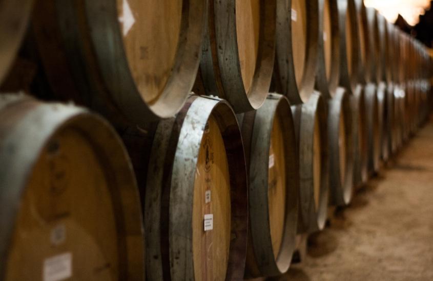 diversos barris de madeira empilhados dentro de galpão de uma das vinícolas no vale dos vinhedos