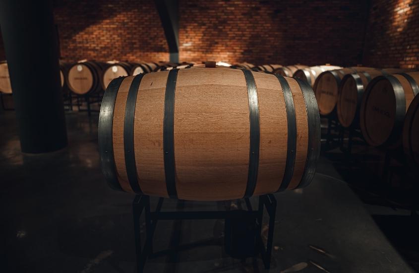 diversos barris de madeira em interior de vinícola, uma opção para quem busca o que fazer no vale dos vinhedos