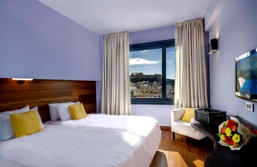 cama de casal e poltrona em suíte com ampla janela com vista para acrópole em Athens Center Square Hotel