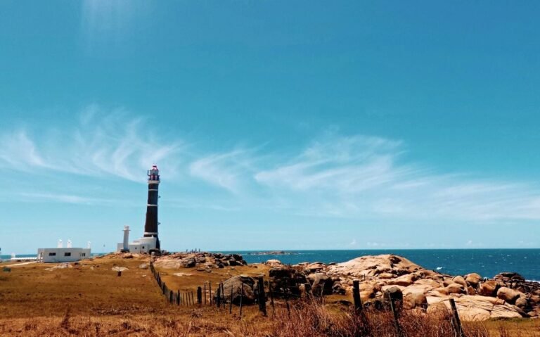 panorâmica de farol em frente ao mar, durante dia ensolarado em um dos destinos no uruguai