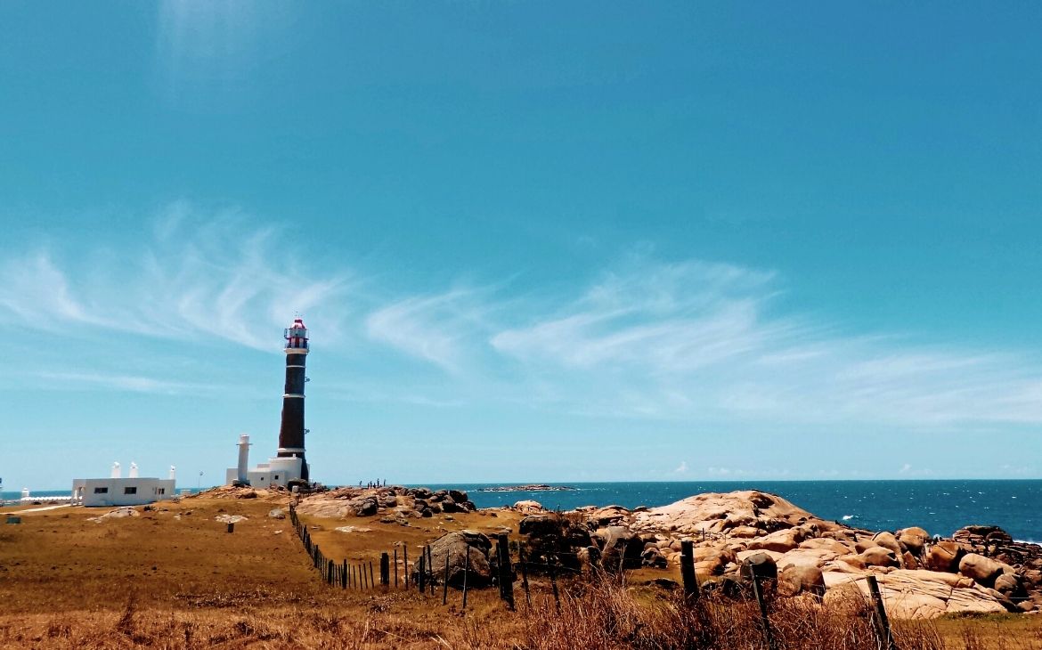 panorâmica de farol em frente ao mar, durante dia ensolarado em um dos destinos no uruguai
