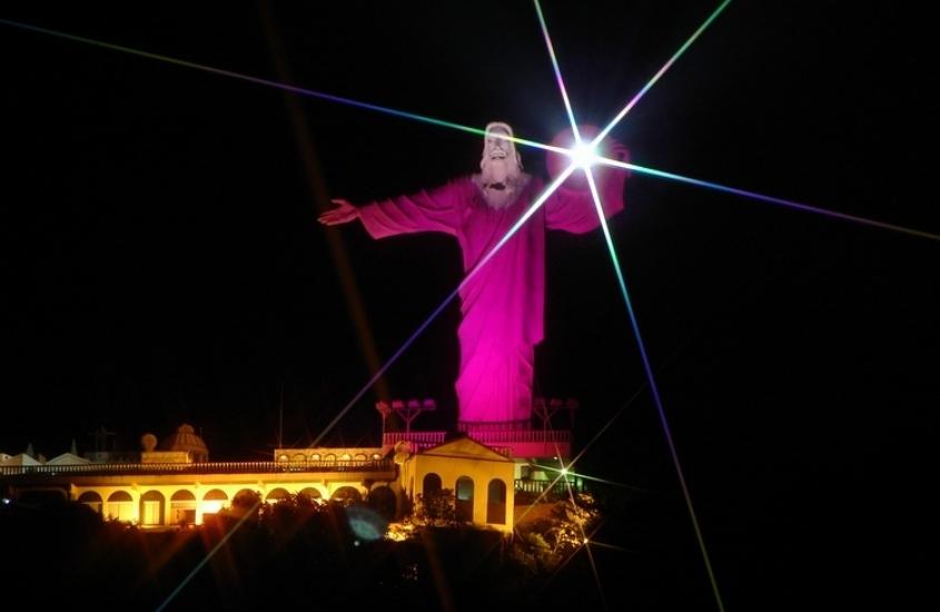 estátua de cristo de 33 metros de altura iluminada por luz rosa, durante a noite em Balneário Camboriú SC