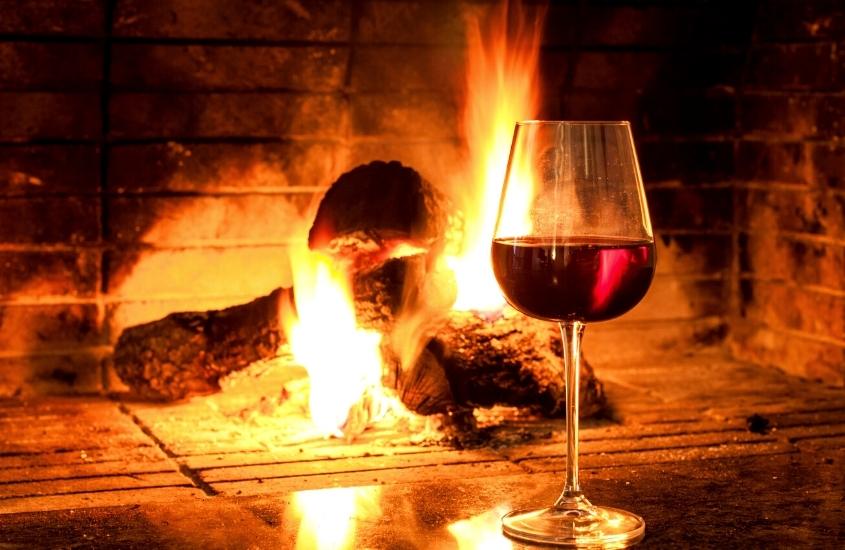 taça de vidro com vinho em frente a lareira, atração ideal ao planejar o que fazer em Blumenau no inverno