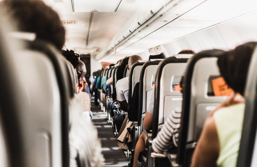 pessoas vistas de costas, sentadas em poltronas de avião em uma viagem para Blumenau