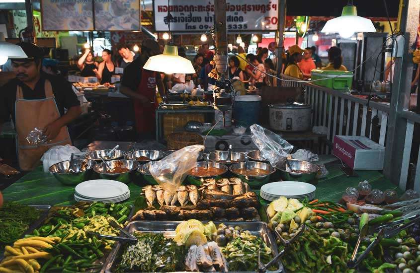 Mercado de alimentos com comidas expostas e pessoas ao redor