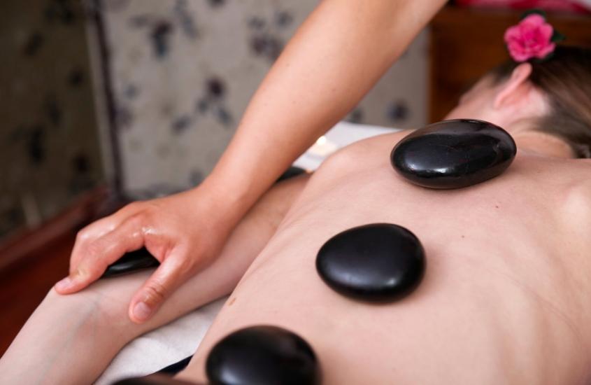 mulher deitada com barriga para baixo em cama de spa, recebe massagem tailandesa