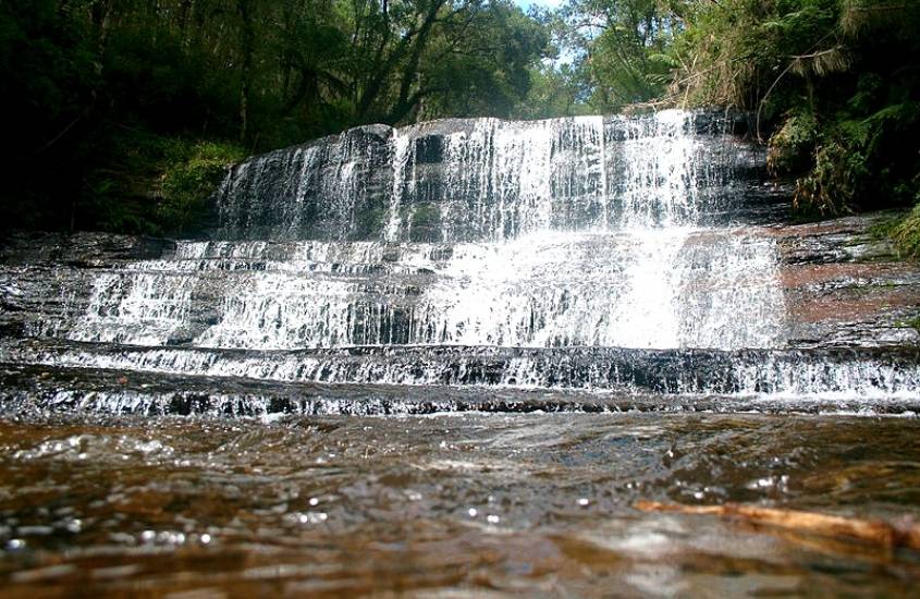 durante o dia, queda d'água de cachoeira desaguando em piscina natural em rio sete quedas, um dos pontos turísticos em urubici sc