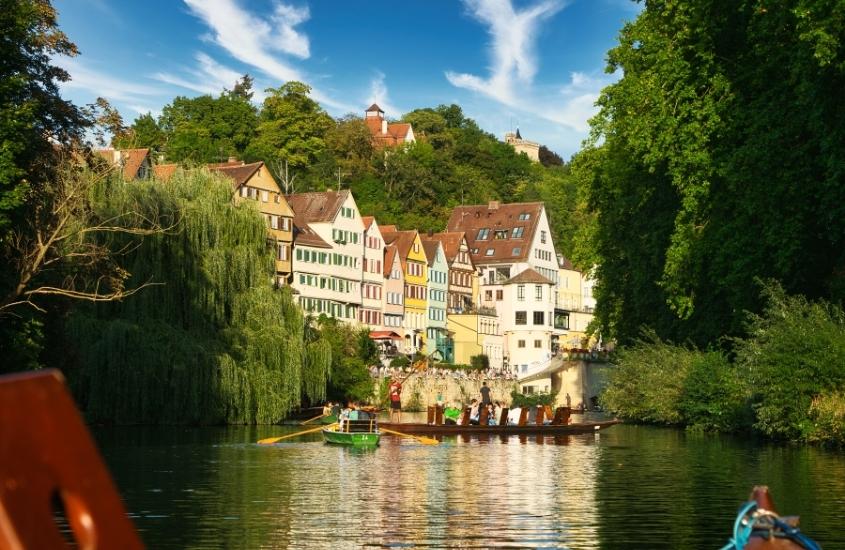 barquinhos em lago, cercado de árvores e casas coloridas ao fundo, durante o dia em tubingen, melhor destino da alemanha no verão