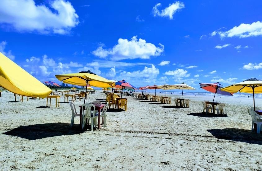 diversas mesas, cadeiras e guarda-sóis em areia de praia em aracaju, durante dia ensolarado