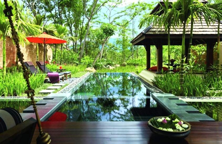 espreguiçadeiras em frente a piscina em meio a natureza em um resort em chiang mai tailândia